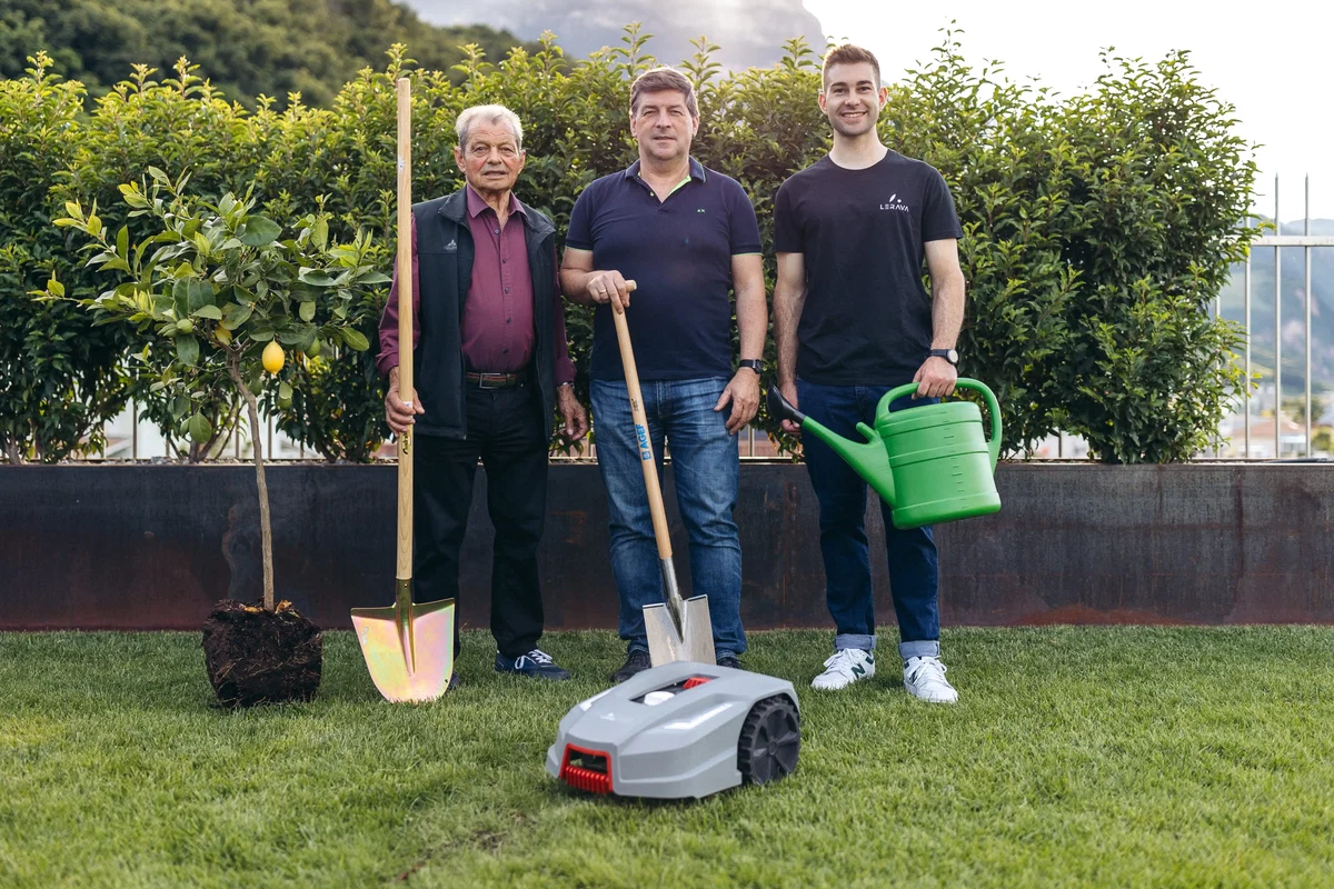 Die Familie Spitaler auf einer gepflegten Rasenfläche mit GPS-Mähroboter